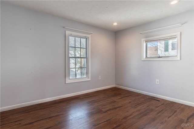 spare room with plenty of natural light, dark wood-type flooring, and a textured ceiling