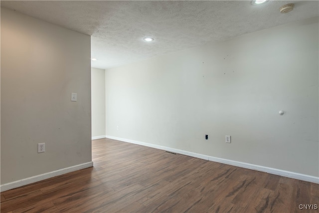 empty room with a textured ceiling and dark wood-type flooring