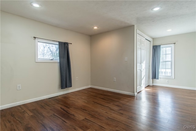 empty room with a textured ceiling, dark hardwood / wood-style floors, and a wealth of natural light