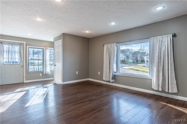 empty room featuring a textured ceiling and dark hardwood / wood-style floors