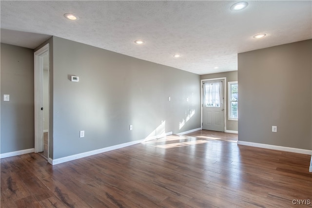 unfurnished room with a textured ceiling and dark hardwood / wood-style floors