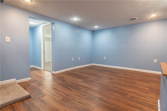 spare room with a textured ceiling and dark wood-type flooring