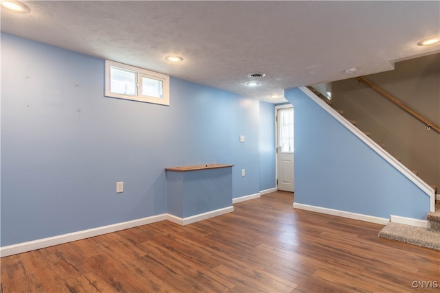 basement featuring hardwood / wood-style floors, plenty of natural light, and a textured ceiling