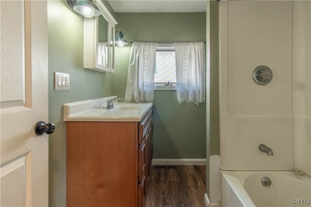 bathroom featuring hardwood / wood-style flooring, vanity, and bathing tub / shower combination