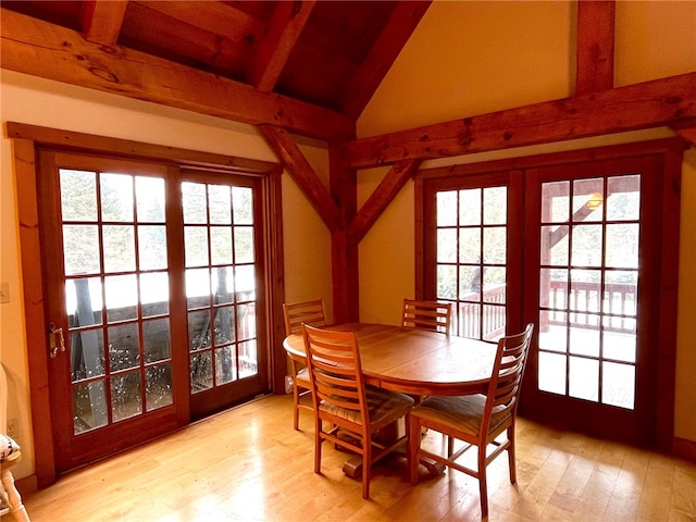 dining room featuring a wealth of natural light, light hardwood / wood-style flooring, lofted ceiling with beams, and french doors