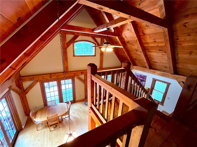 stairs with hardwood / wood-style flooring, a healthy amount of sunlight, beamed ceiling, and high vaulted ceiling