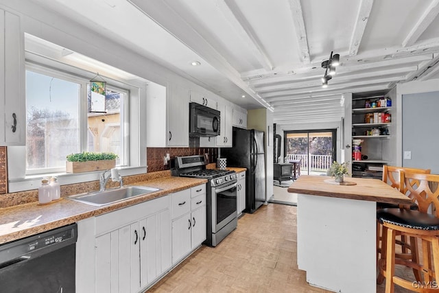 kitchen featuring sink, white cabinetry, a breakfast bar area, and black appliances