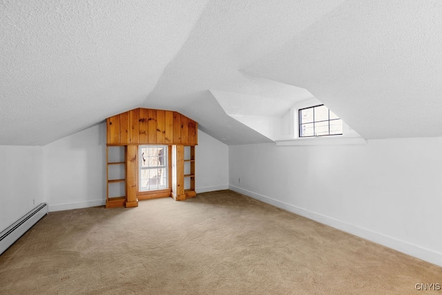 additional living space featuring a healthy amount of sunlight, lofted ceiling, light carpet, and a baseboard heating unit