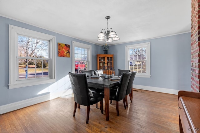 dining space with hardwood / wood-style floors, ornamental molding, a wealth of natural light, and a notable chandelier