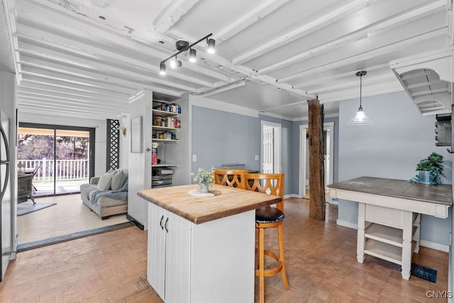 kitchen with light parquet flooring, crown molding, pendant lighting, a kitchen bar, and white cabinets