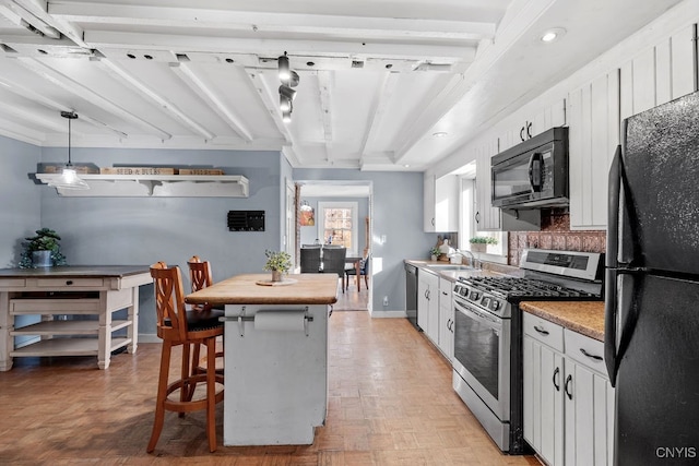 kitchen featuring pendant lighting, black appliances, white cabinets, sink, and light parquet flooring