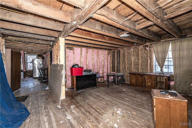 basement with dark hardwood / wood-style floors and stainless steel refrigerator