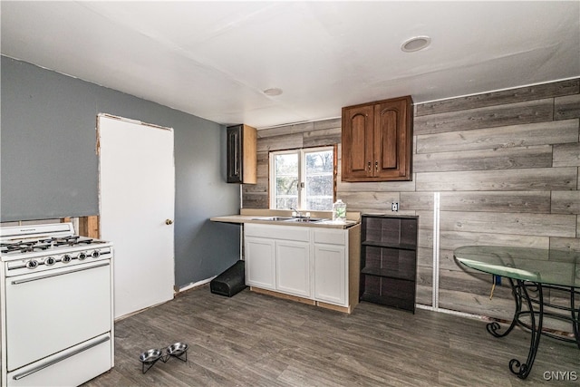 kitchen with white cabinets, sink, wooden walls, dark hardwood / wood-style floors, and white range with gas cooktop