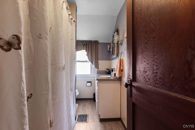 laundry room featuring light tile patterned floors, tile walls, and sink