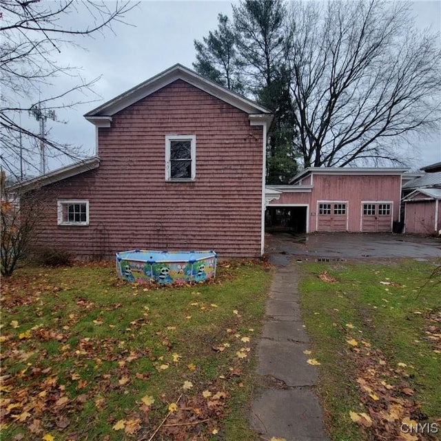 view of side of home featuring a lawn, an outbuilding, and a garage