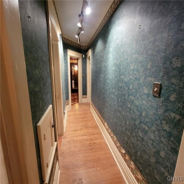 corridor with light wood-type flooring and track lighting