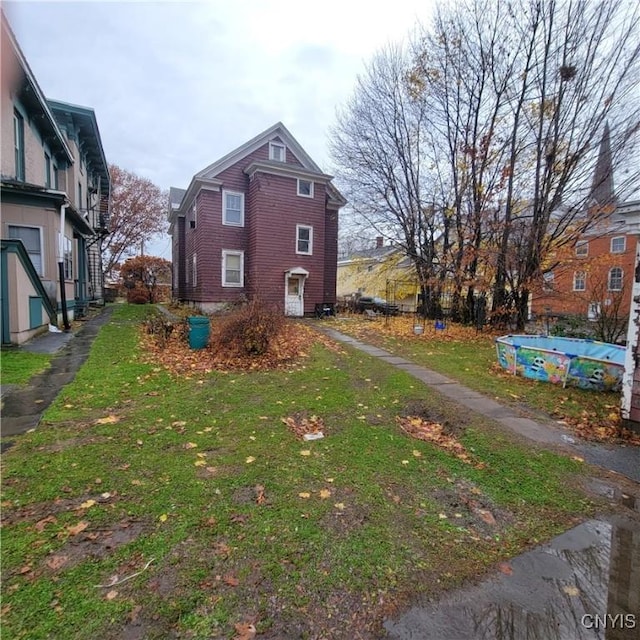 view of side of home with a yard and a covered pool