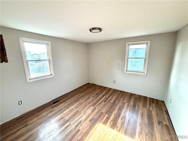 unfurnished room with dark hardwood / wood-style floors and a healthy amount of sunlight