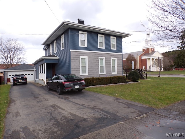 view of property with a garage, an outbuilding, and a front lawn