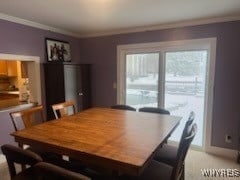 carpeted dining space with crown molding