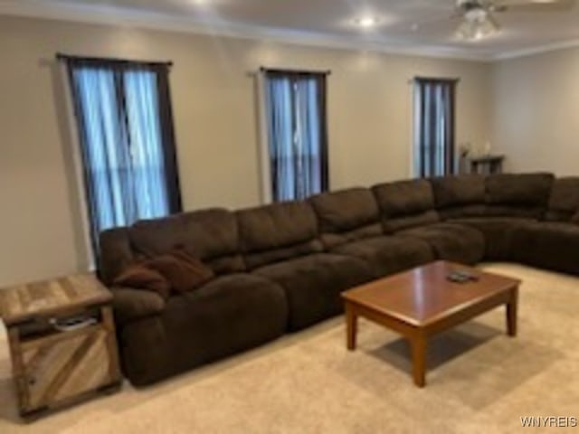 living room featuring ceiling fan, ornamental molding, and light carpet