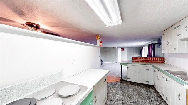 kitchen featuring kitchen peninsula, sink, white cabinetry, and a textured ceiling