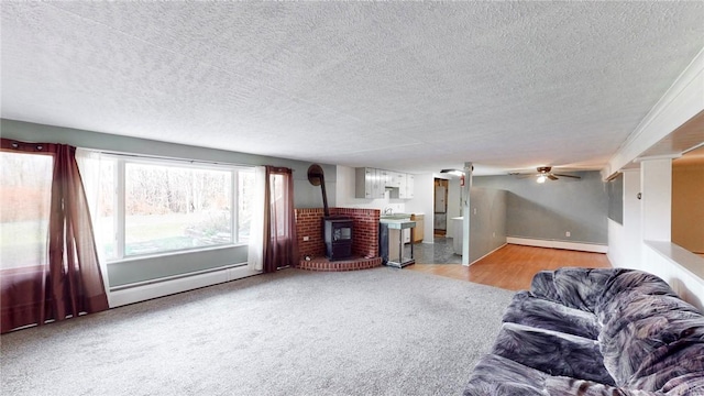 living room with light wood-type flooring, a wood stove, a textured ceiling, and a baseboard heating unit