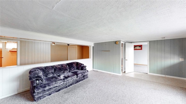 living area featuring wooden walls, carpet floors, and a textured ceiling