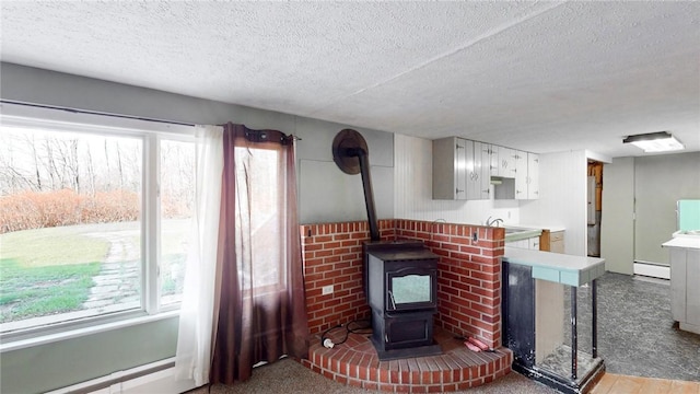 living room with a textured ceiling, a wood stove, and plenty of natural light