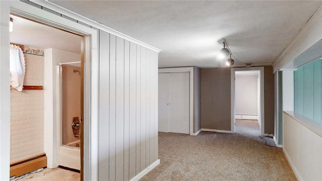 corridor with light colored carpet, baseboard heating, and brick wall