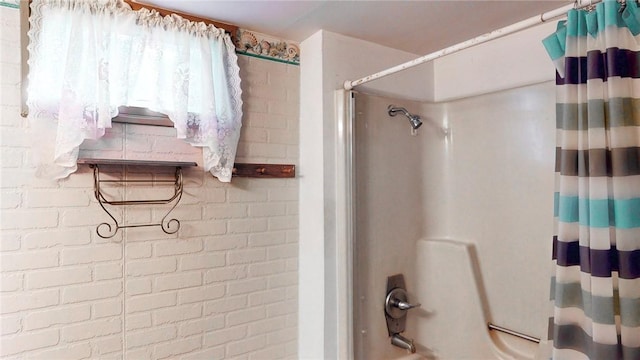 bathroom featuring shower / bathtub combination with curtain and brick wall