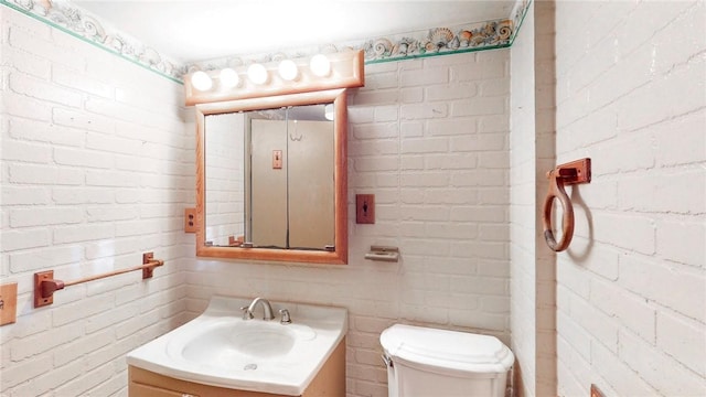 bathroom with vanity, toilet, and brick wall