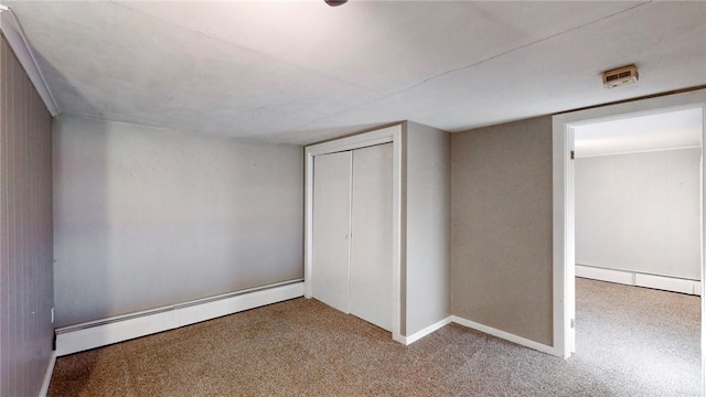 unfurnished bedroom featuring baseboard heating, a closet, and carpet