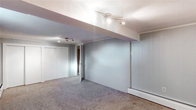 basement with carpet flooring, crown molding, and a baseboard heating unit