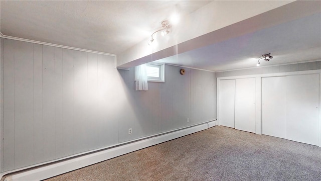 basement with carpet floors, wooden walls, and a baseboard heating unit