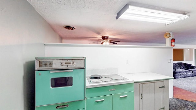 kitchen featuring ceiling fan, wall oven, a textured ceiling, white electric stovetop, and green cabinetry