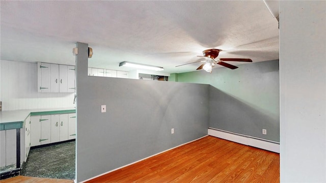 unfurnished room featuring ceiling fan, light hardwood / wood-style floors, a textured ceiling, and a baseboard radiator