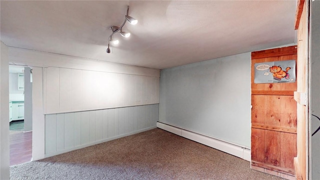 basement with baseboard heating, wood walls, and light colored carpet