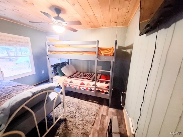 bedroom with ceiling fan, light hardwood / wood-style floors, wooden ceiling, and wooden walls