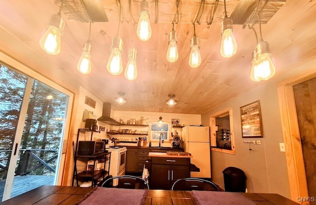 kitchen with sink, white appliances, hanging light fixtures, and range hood