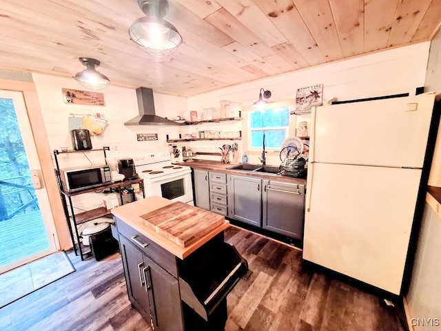 kitchen featuring white appliances, sink, wall chimney range hood, hardwood / wood-style floors, and butcher block counters