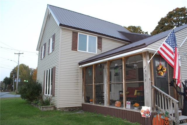 back of property with a sunroom and a yard