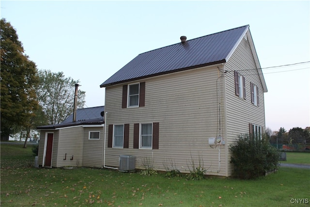 rear view of property featuring a yard and central air condition unit