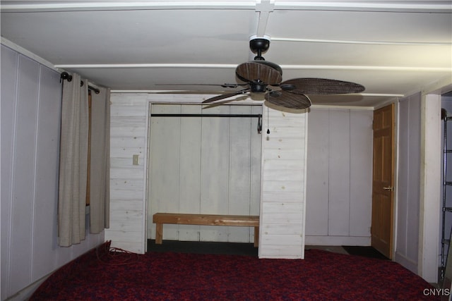 unfurnished bedroom with ceiling fan and wooden walls