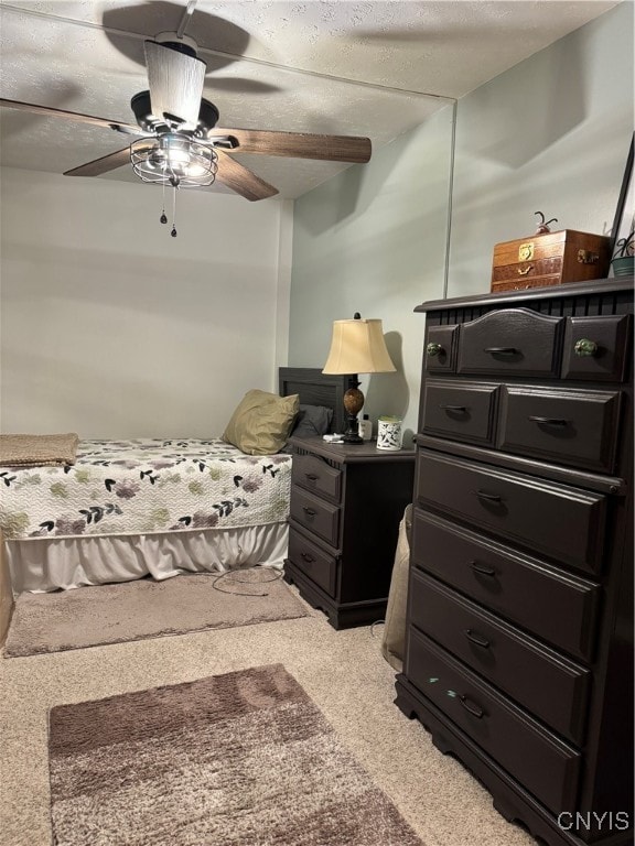 carpeted bedroom featuring ceiling fan and a textured ceiling