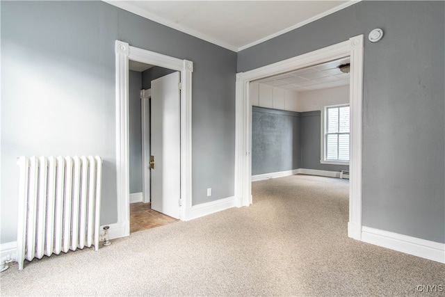 empty room with light colored carpet, ornamental molding, radiator, and a baseboard radiator