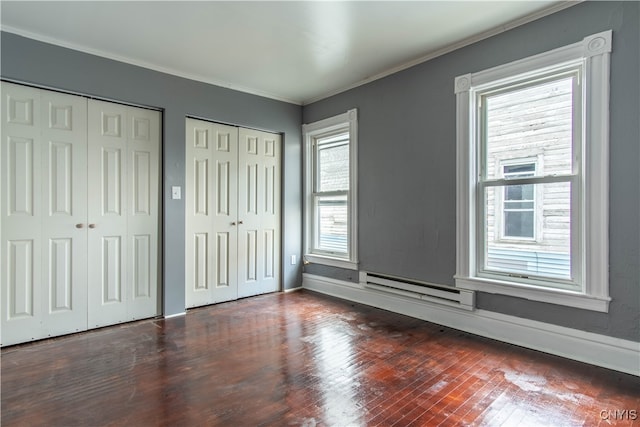 unfurnished bedroom with crown molding, multiple closets, baseboard heating, and multiple windows