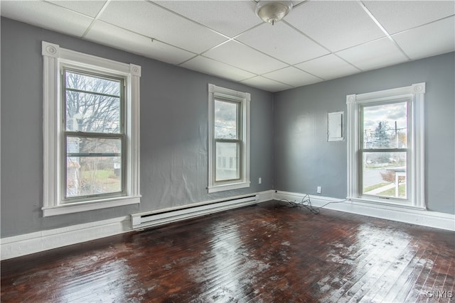 spare room with a drop ceiling, a baseboard radiator, and hardwood / wood-style flooring