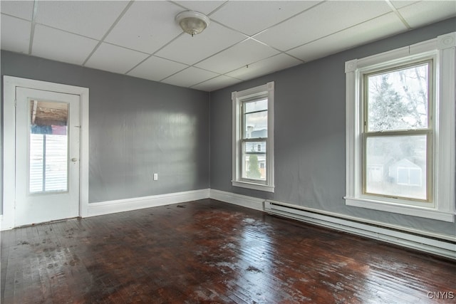 empty room with a paneled ceiling, a baseboard radiator, and hardwood / wood-style flooring