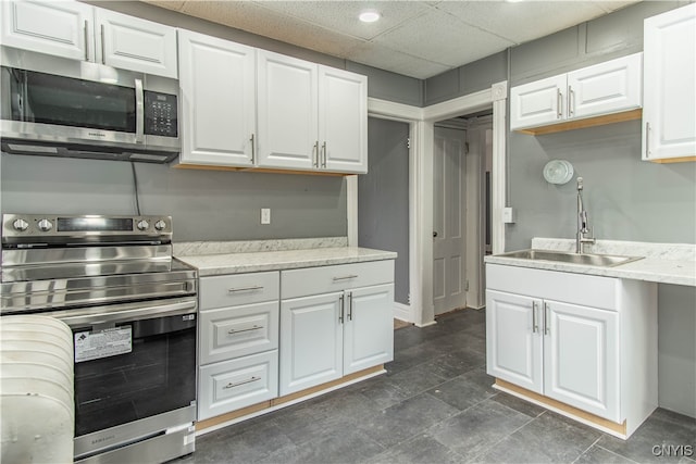 kitchen featuring appliances with stainless steel finishes, a paneled ceiling, white cabinetry, and sink